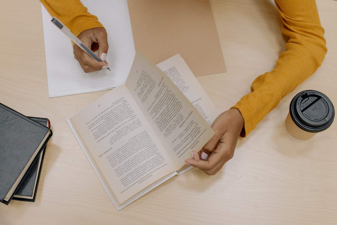 Person reading a book and writing notes - QCE English Essay