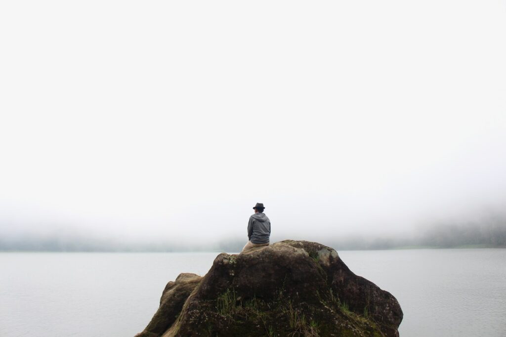 Loneliness - person sitting on a rock by themselves